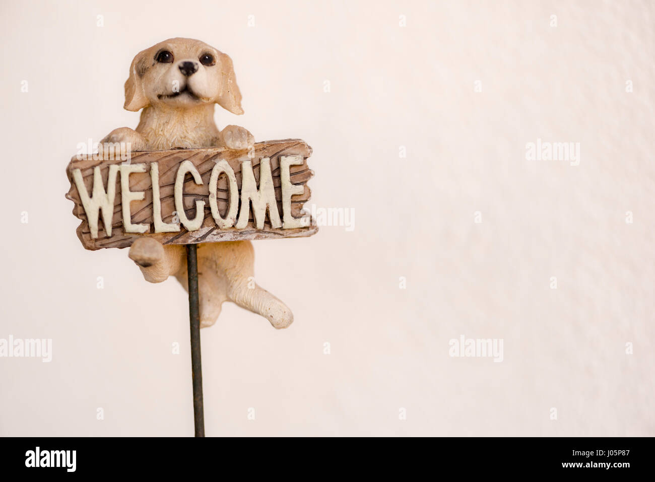 Cane in legno con un segno accogliente la nostra casa Foto Stock