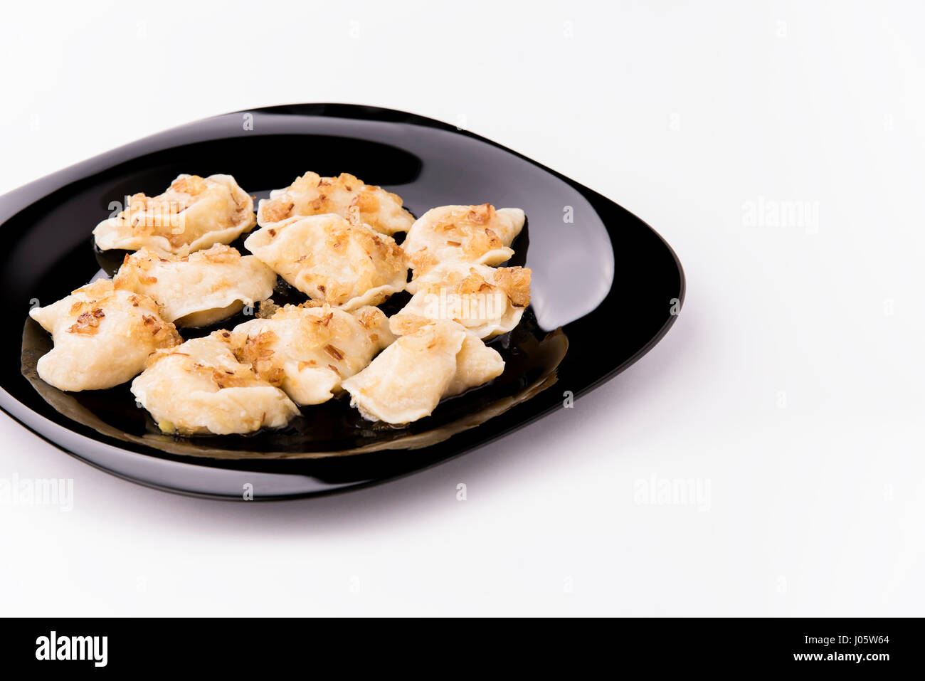 Gnocchi di fresco su una piastra nera condito con croccante di cipolle. L'Ucraina Foto Stock