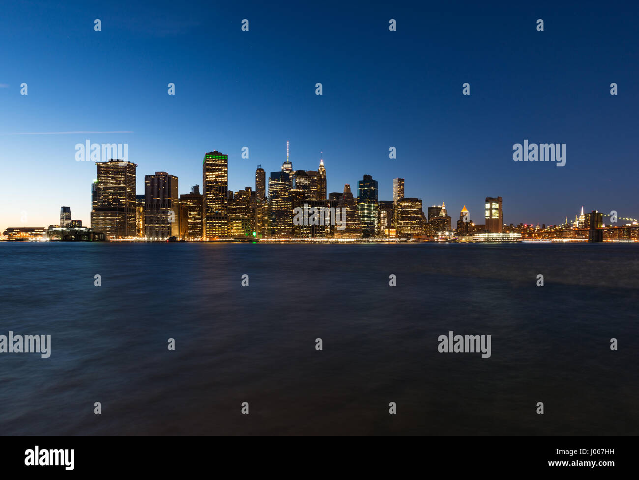 La parte inferiore di Manhattan skyline al tramonto con East River in primo piano, New York, Stati Uniti d'America Foto Stock