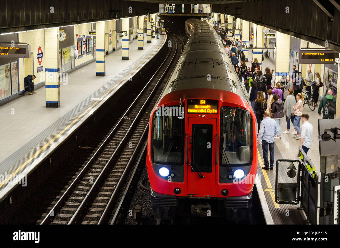 Un treno arriva alla piattaforma di dalla fermata della metropolitana Aldgate East London dove i passeggeri sono in attesa. Foto Stock