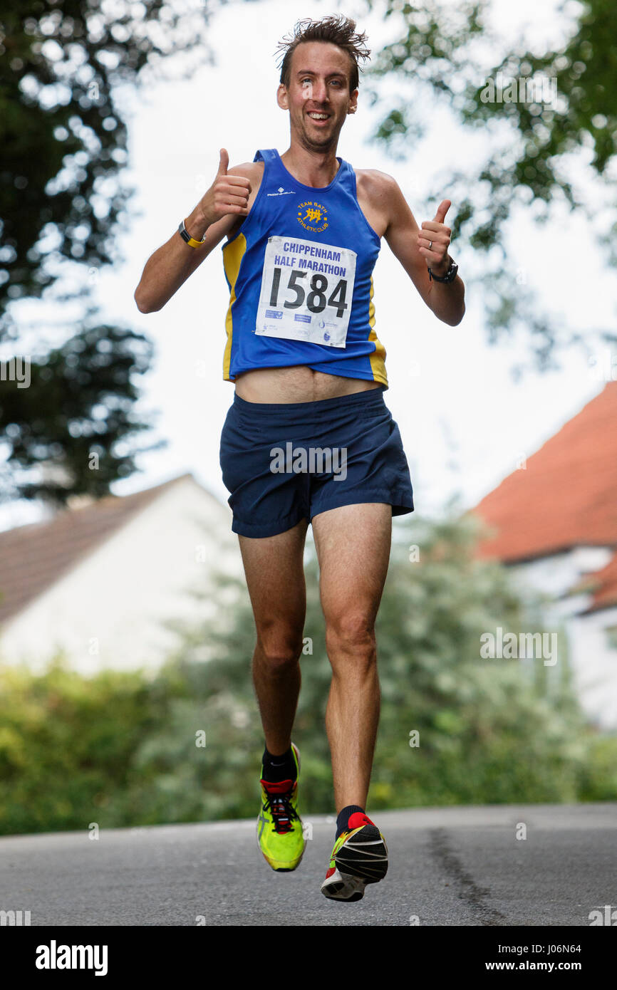 Un atleta maschio indossa pantaloncini in esecuzione e abbigliamento sportivo è raffigurato come lui corre in una mezza maratona corsa su strada in Chippenham, England, Regno Unito Foto Stock