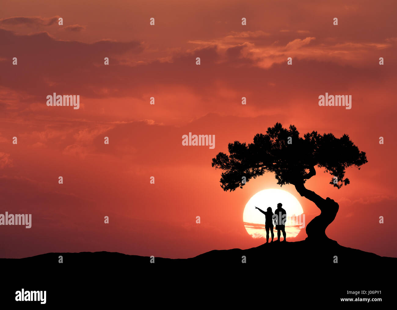 Le persone sotto l'albero storto sullo sfondo di sun. Silhouette di una coppia permanente sulla montagna, albero e colorato red sky con nuvole a suns Foto Stock