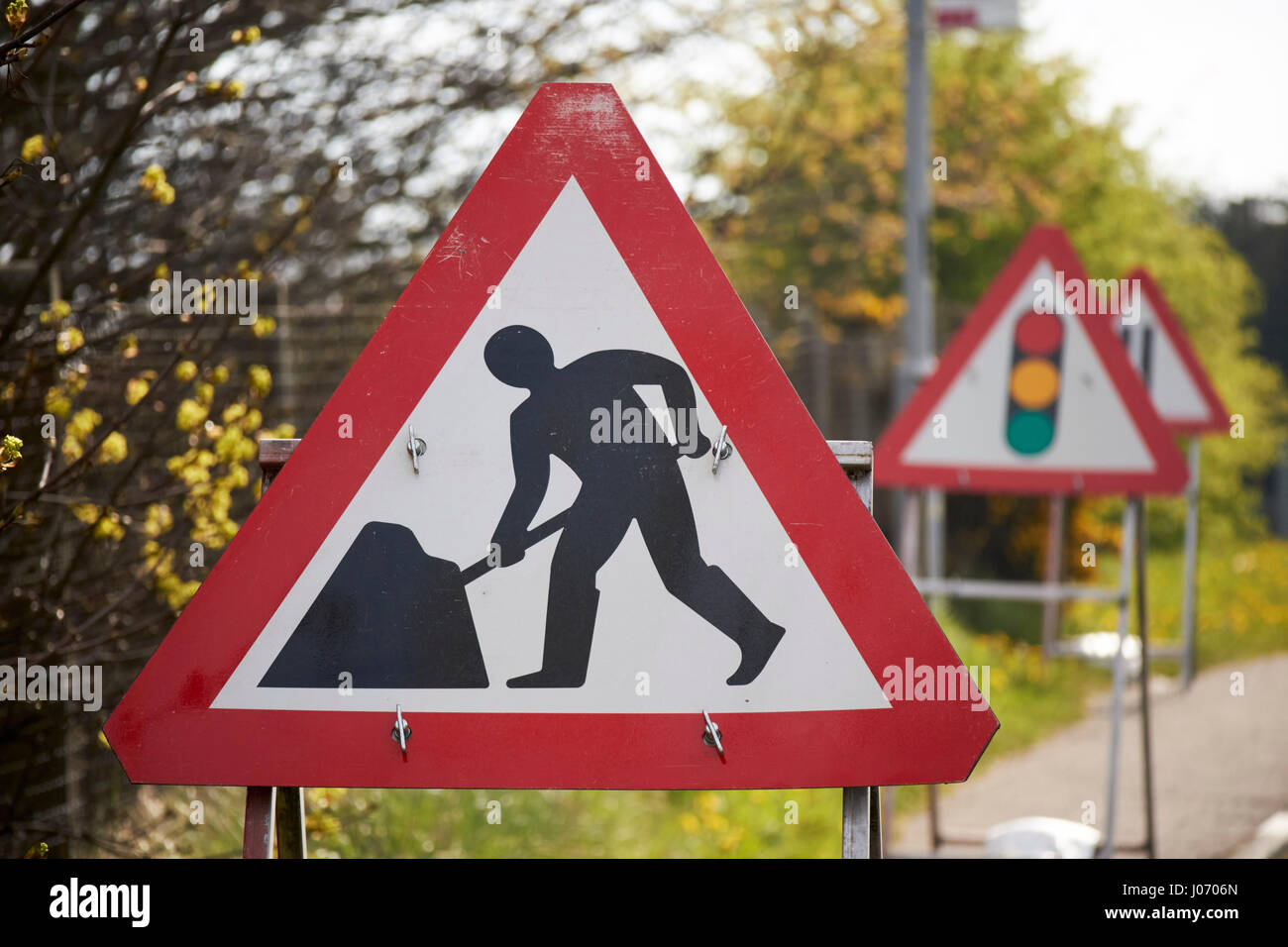 Gli uomini al lavoro temporaneo del traffico di costruzione segnali di avvertimento a Newtownabbey Regno Unito Foto Stock
