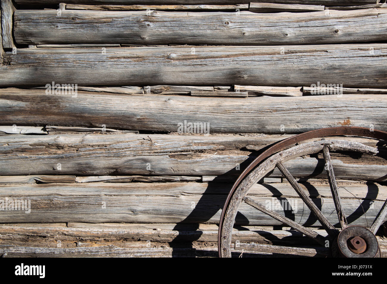 Tagliato a mano vecchi log e chinking dalla vecchia cabina occidentale e ruota di carro barnwood Foto Stock