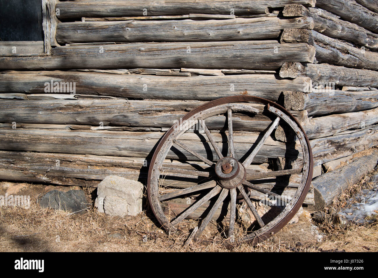 Tagliato a mano vecchi log e chinking dalla vecchia cabina occidentale e ruota di carro barnwood Foto Stock