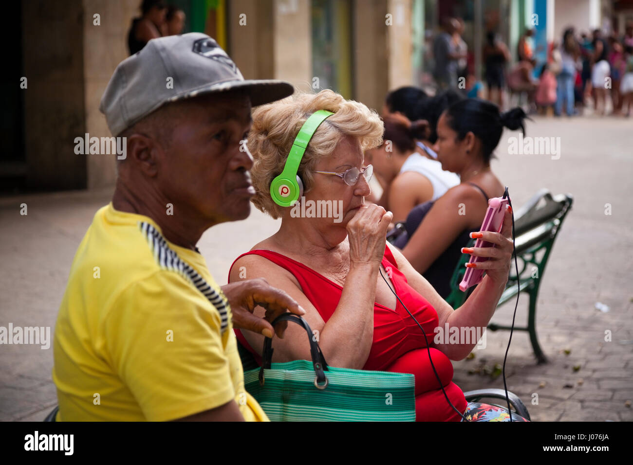 Una donna cubana guarda il suo smartphone mentre si utilizza Beats by Dre Headphones in Old Havana, Cuba. Foto Stock
