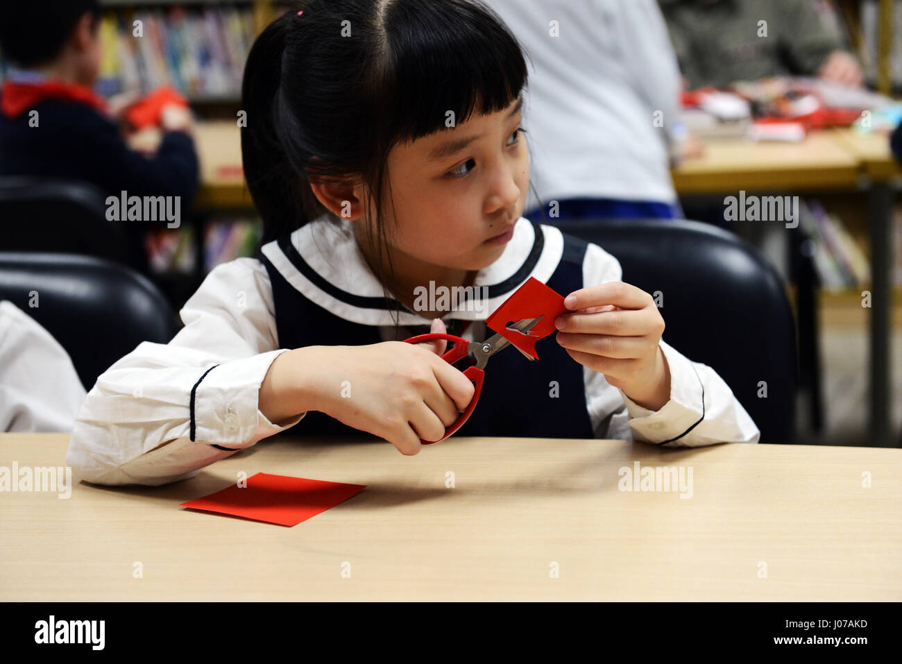 Bambini imparare l arte del Jianzhi- Cinese tradizionale taglio della carta. Foto Stock