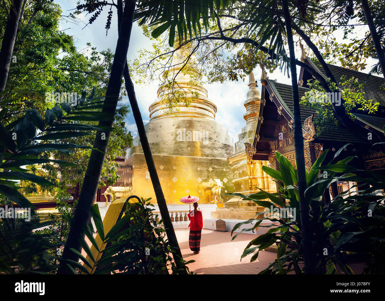 Donna con turistico rosso tailandese tradizionale ombrellone vicino a Golden tempio Wat Phra Singh in Chiang Mai Thailandia Foto Stock