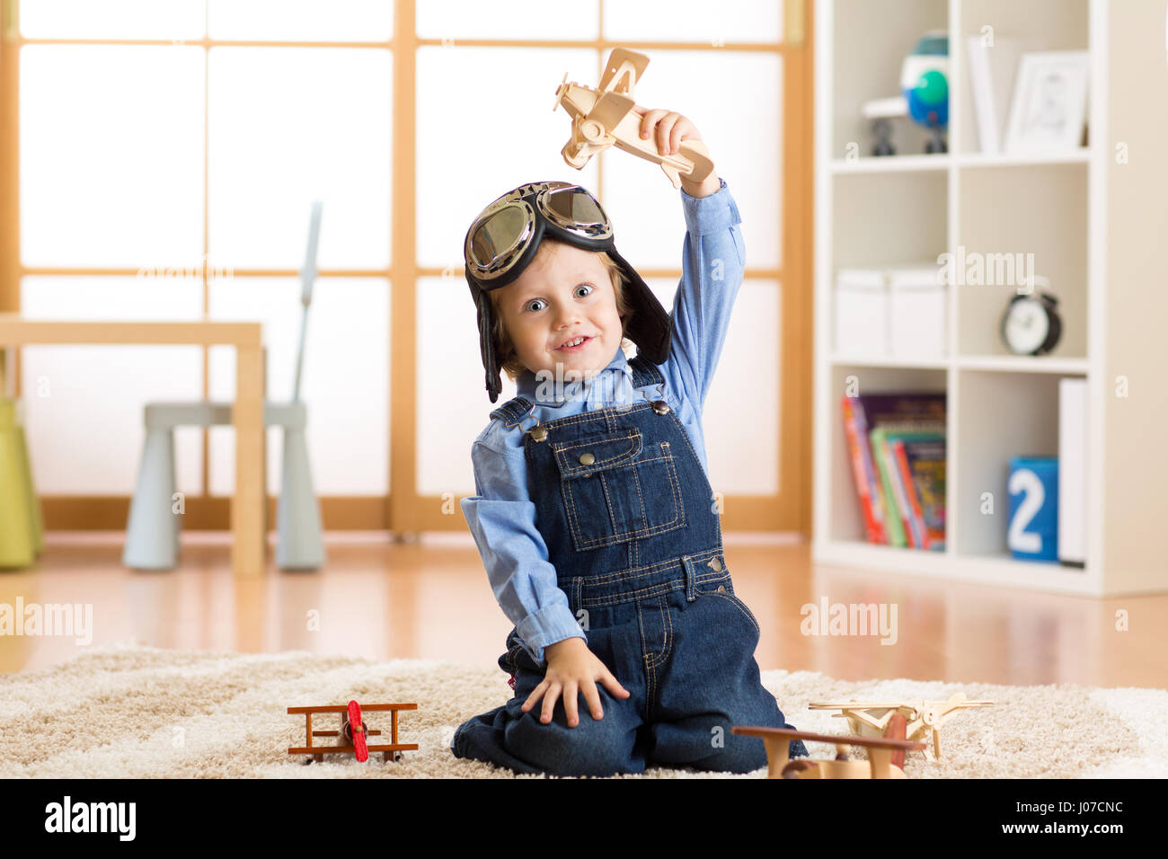 Capretto felice toddler giocando con aeroplano giocattolo e sogna di diventare un pilota Foto Stock