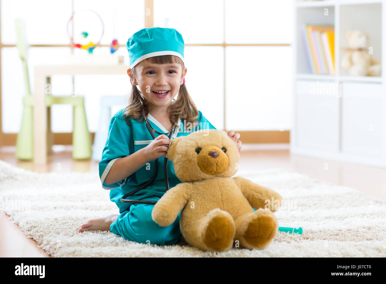 Carino kid girl riproduzione medico con il giocattolo di peluche a casa Foto Stock