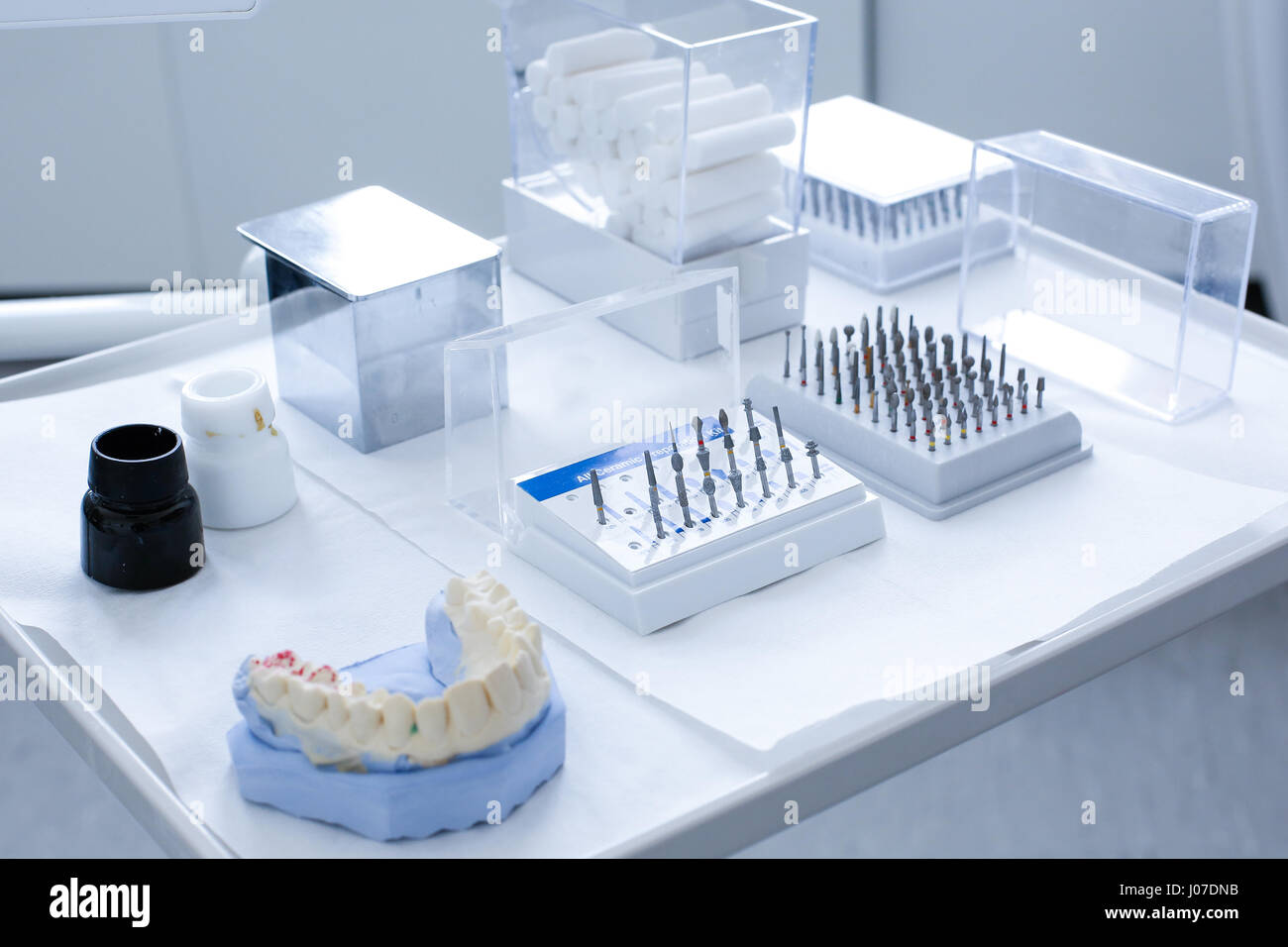 Varietà di strumenti in studio dentistico: ceramica kit preparazione e varie frese dentali con stampo dentale su un vassoio Foto Stock