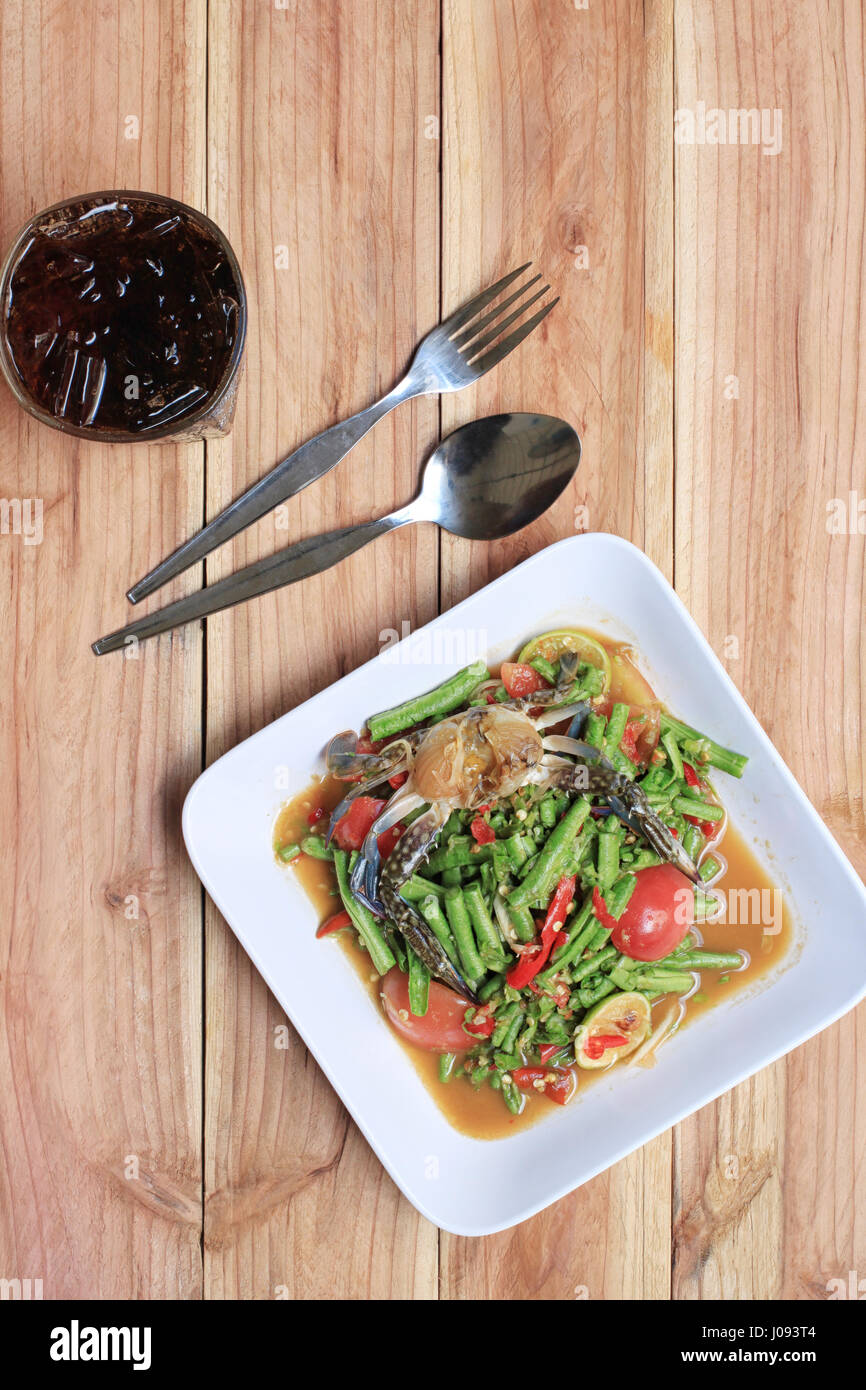 Yardlong insalata di fagioli con il granchio di thai gli alimenti nel piatto bianco su uno sfondo di legno, SOMTUM è il cibo di popolari in Thailandia. Foto Stock