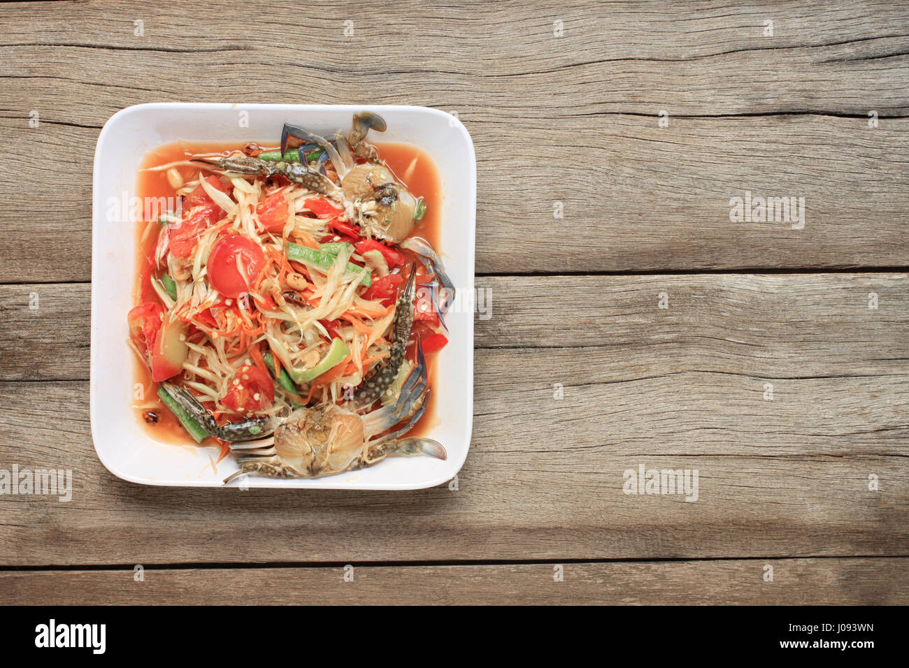 Insalata di papaia con il granchio di thai gli alimenti nel piatto bianco su uno sfondo di legno, SOMTUM Thai è il cibo di popolari in Thailandia. Foto Stock