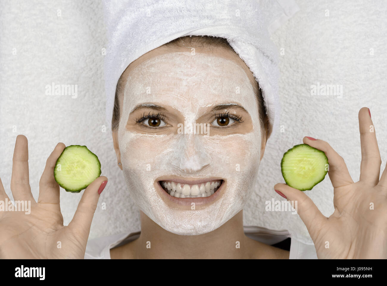 Donna con fette di cetriolo e cosmetic skincare maschera facciale Foto Stock