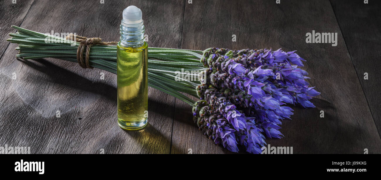 Freschi di fiori di lavanda e olio essenziale come aromaterapia naturale per il mal di testa ed emicrania di rilievo sul vecchio sfondo di legno Foto Stock