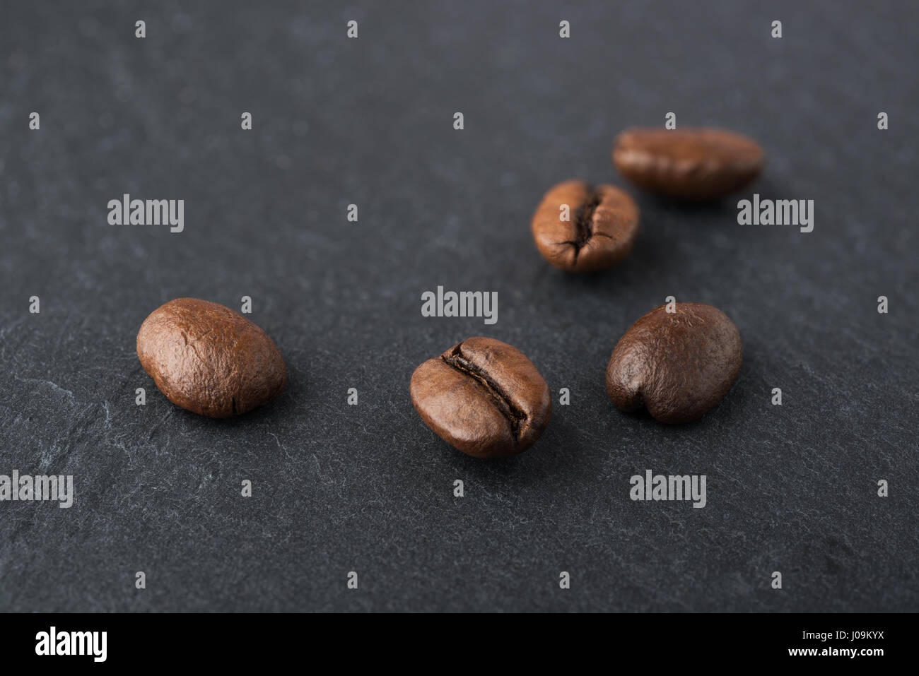 Alcuni chicchi di caffè tostati macro shot su una pietra nera piastra di ardesia Foto Stock