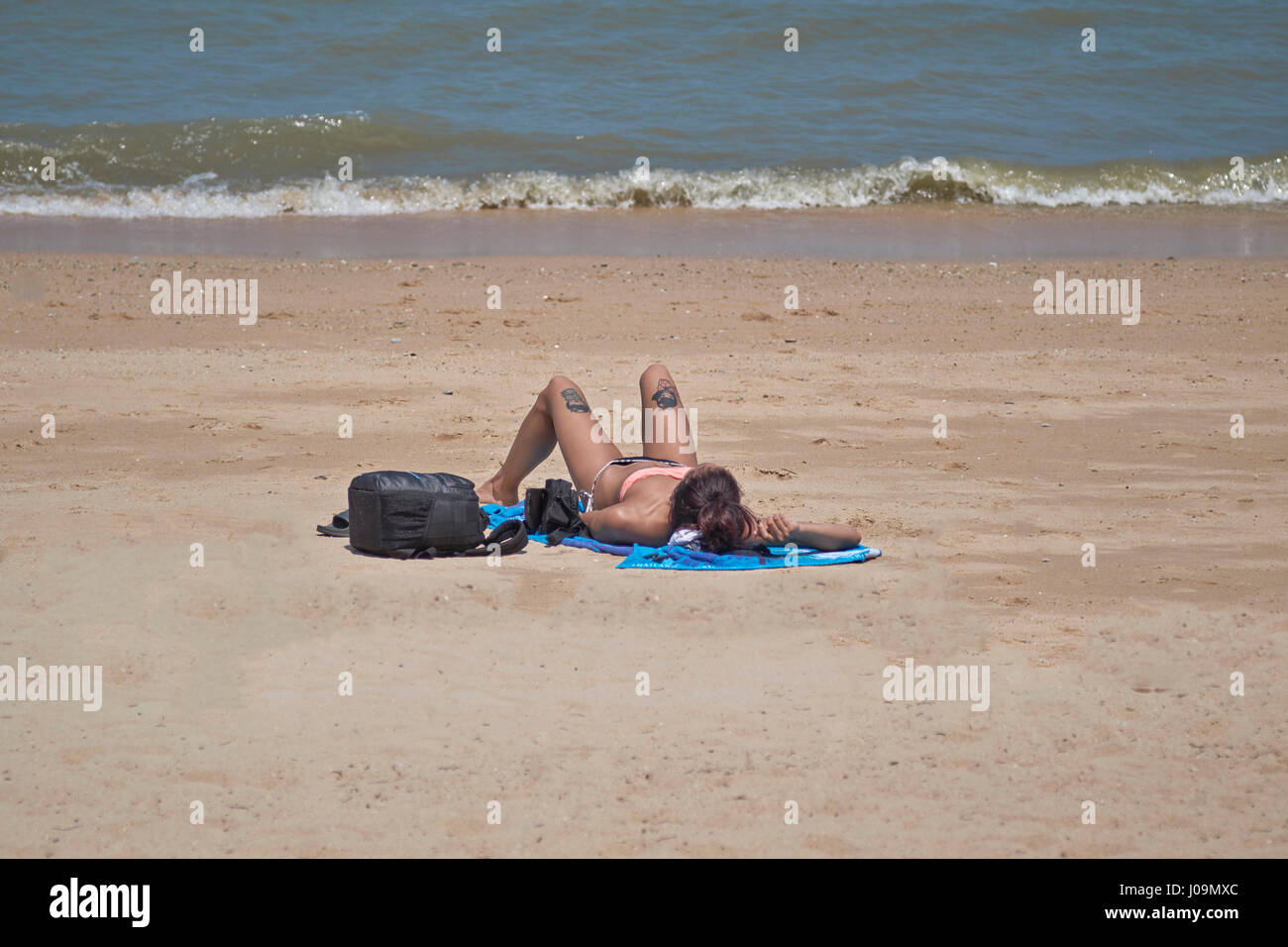 Donna sola su una spiaggia a prendere il sole. Foto Stock