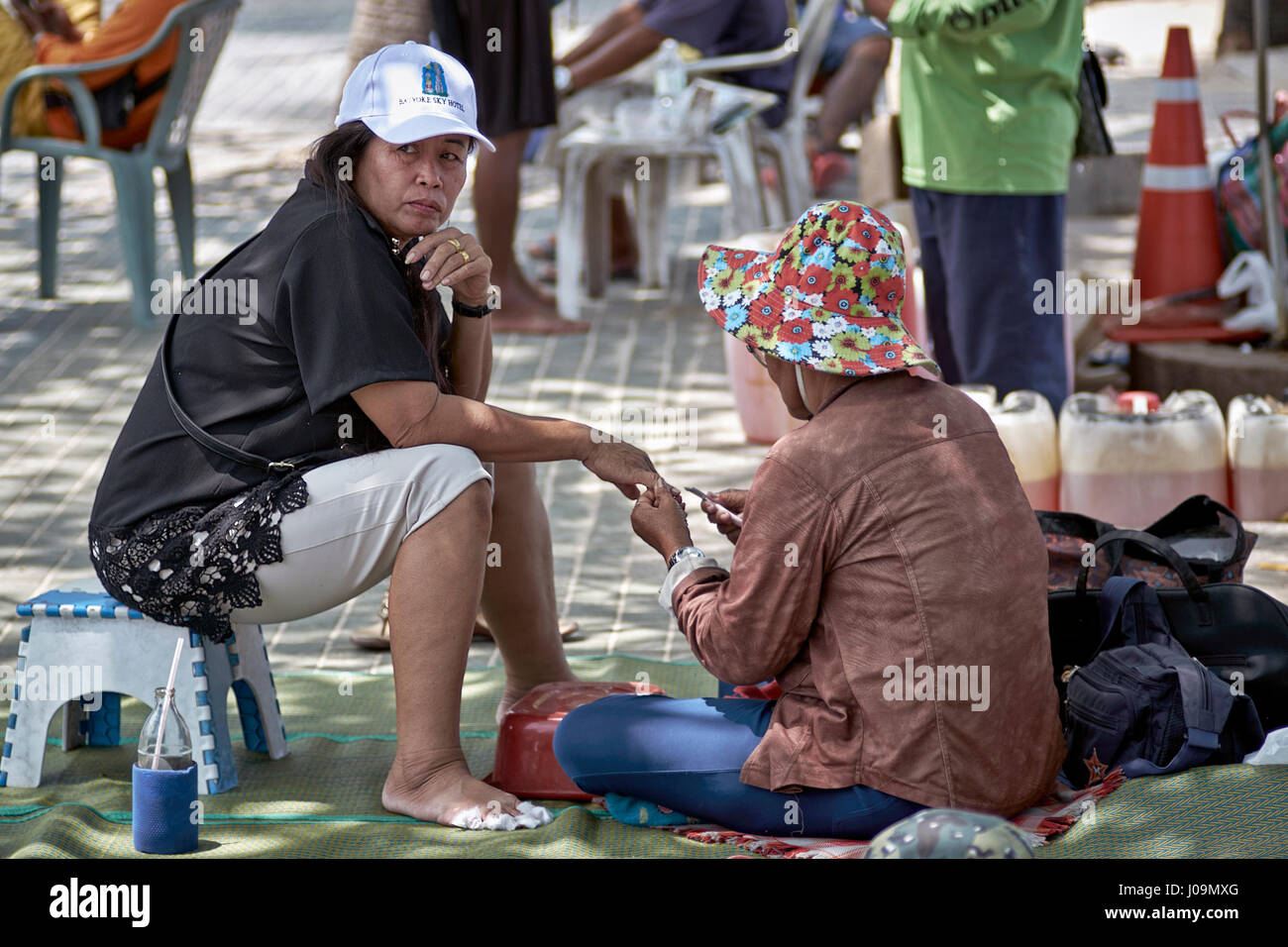 Donna avente una manicure e pedicure su una strada in Thailandia. Sud-est asiatico Foto Stock