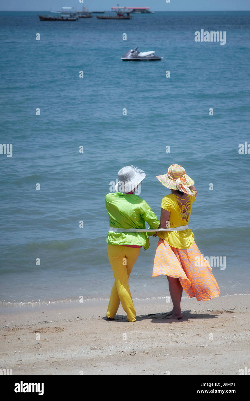 Due donne amiche sulla spiaggia. Donna in abiti estivi colorati, con vista sul mare. Foto Stock