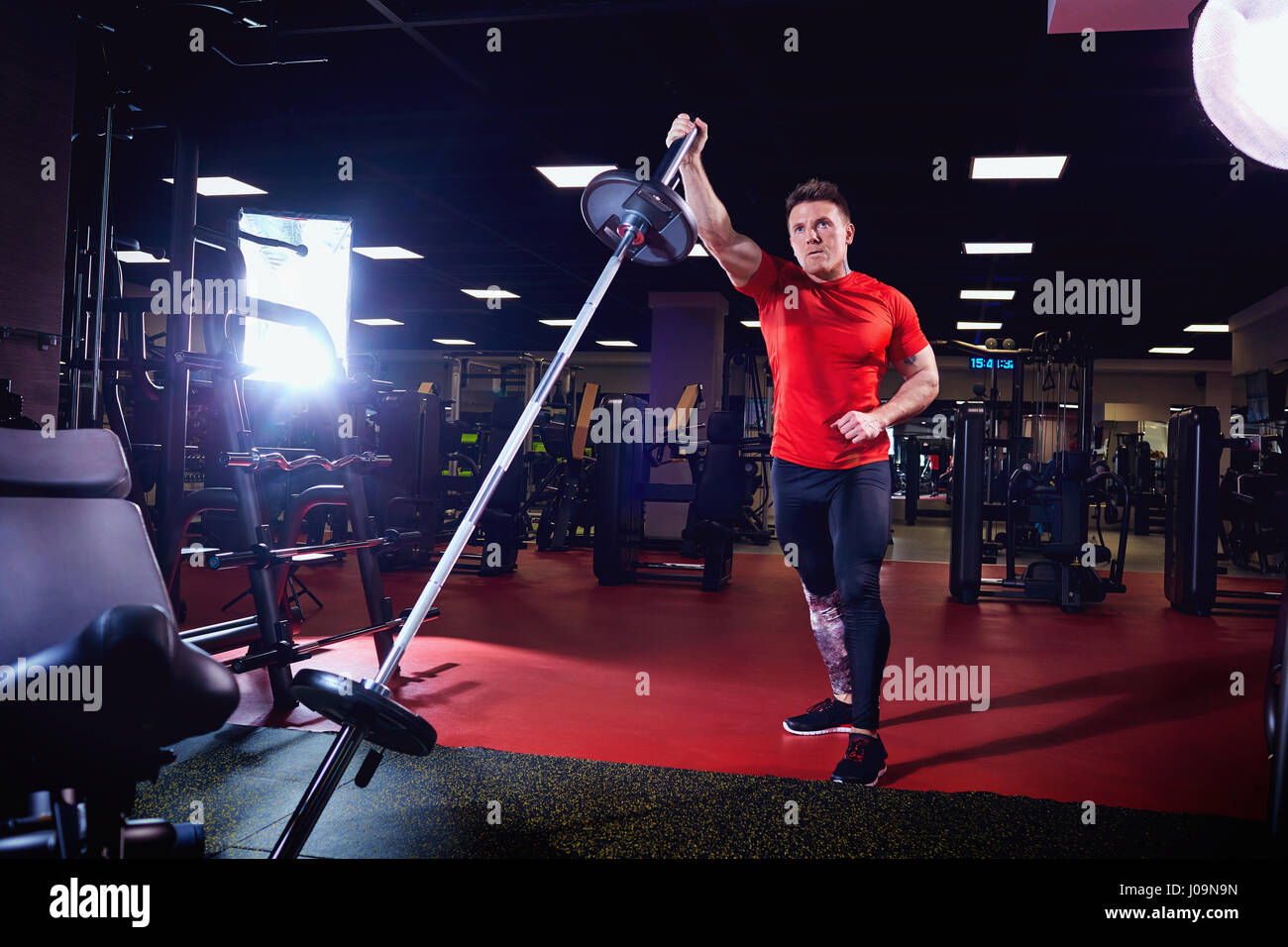Atletica atleta maschio a fare gli esercizi con un barbell in palestra Foto Stock