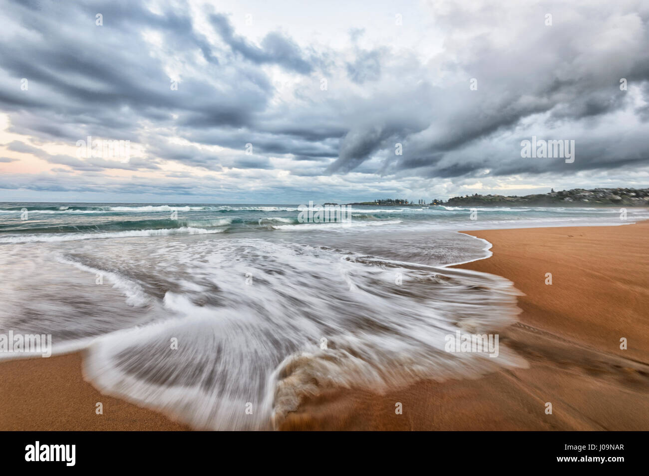 Drammatica vista di un imminente tempesta e le onde motion blur a Bombo Beach, Kiama, Illawarra Costa, Nuovo Galles del Sud, NSW, Australia Foto Stock