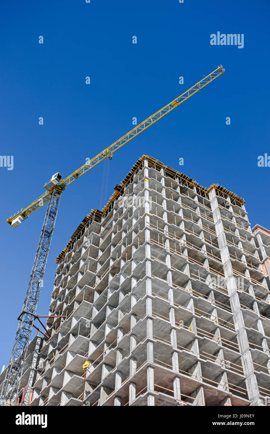 Sito in costruzione con incompiuto edificio residenziale e grandi gru a torre Foto Stock