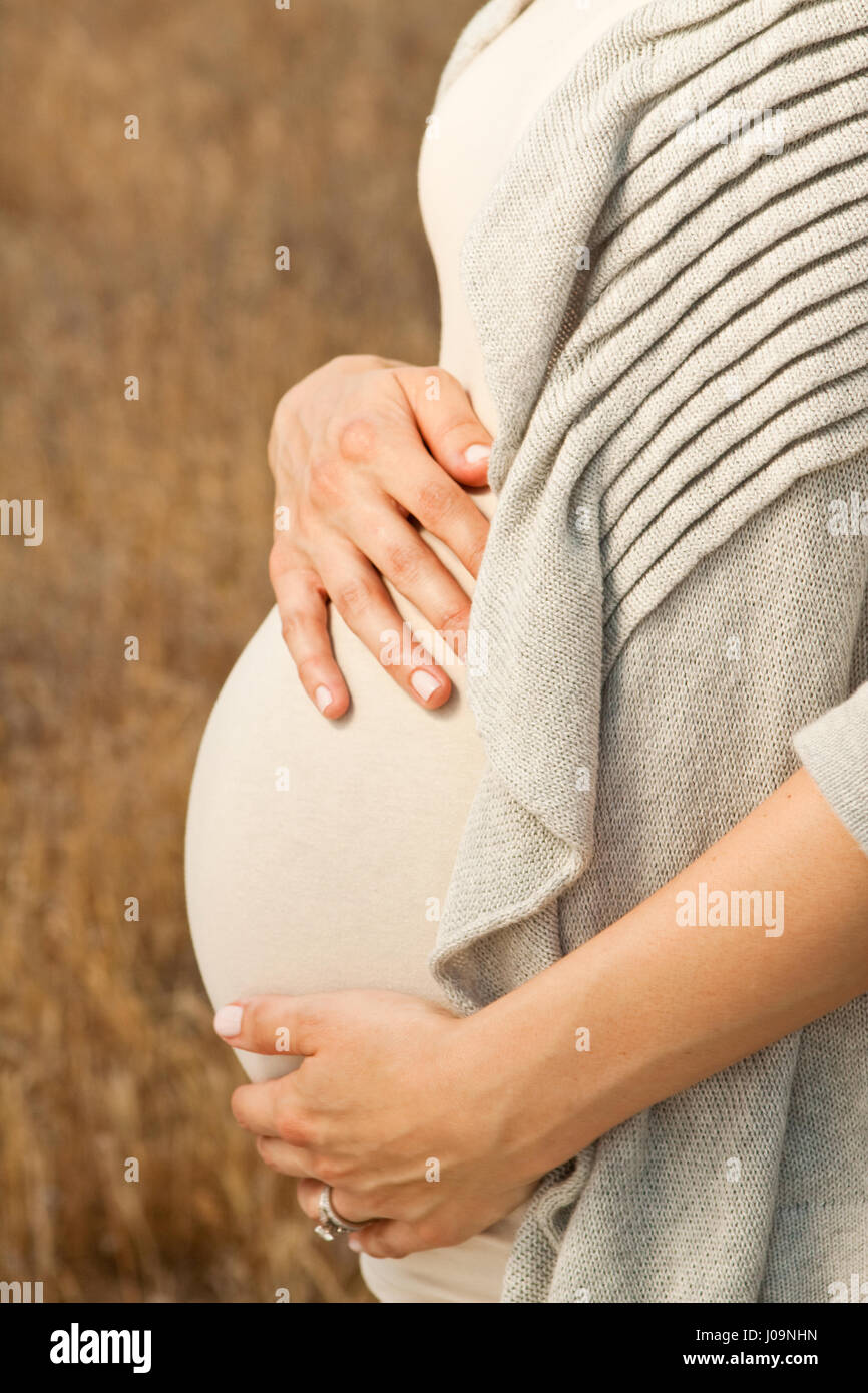 Donna incinta fuori mentre tiene il suo ventre. Foto Stock