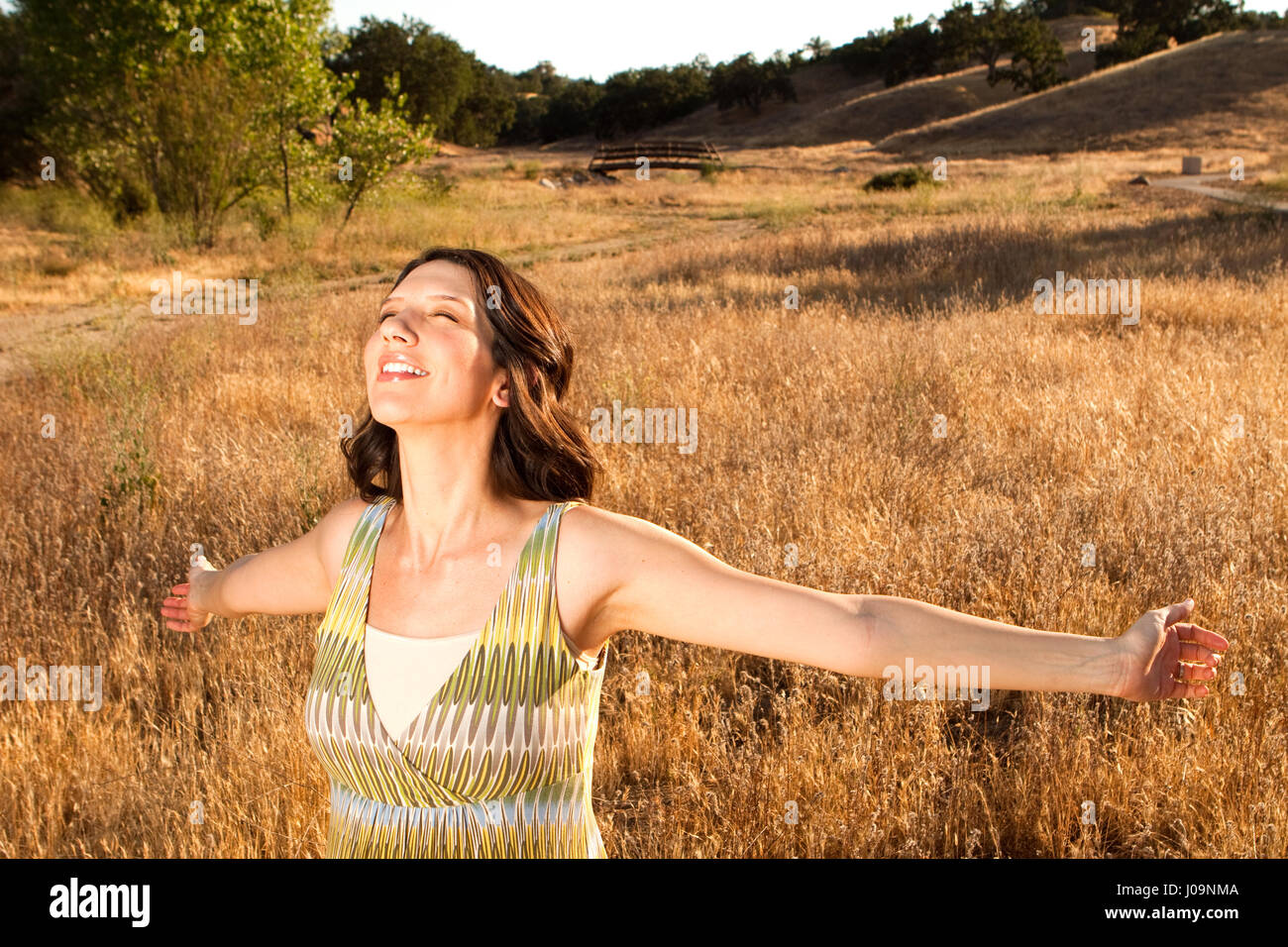 Bella donna in un campo con le braccia aperte. Foto Stock
