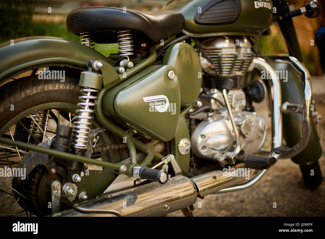 Primo piano della motocicletta Royal Enfield Classic 500 verde oliva con logo della copertina laterale e motore cromato Foto Stock