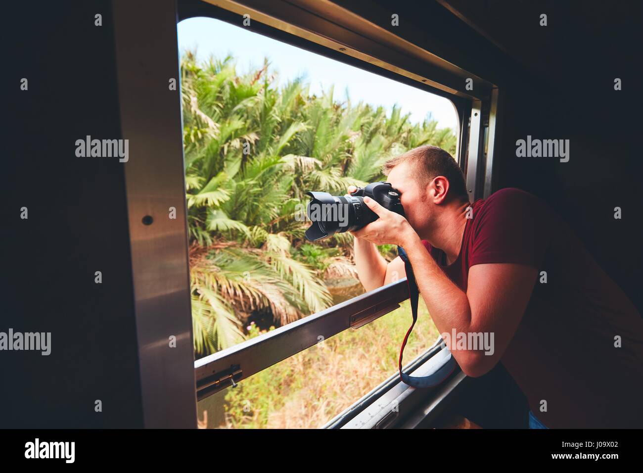 I giovani ospiti in vacanza. Fotografo con fotocamera DSLR photoshooting dalla finestra aperta del treno vintage. Foto Stock