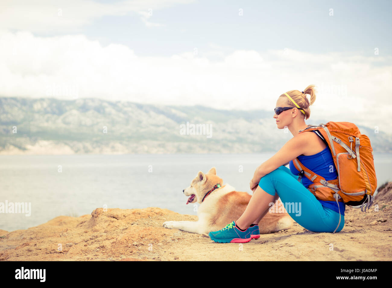 Donna escursionismo con akita inu cane sul sentiero sul mare. Ricreazione e uno stile di vita sano all'aperto in estate sulle montagne e mare natura. Bella inspirationa Foto Stock