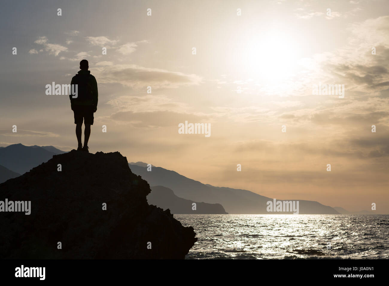 Escursionista o runner silhouette backpacker, un uomo in cerca di ispirazione paesaggio oceano e isole sul picco di montagna. Uomo realizzato celebrare la bella Foto Stock