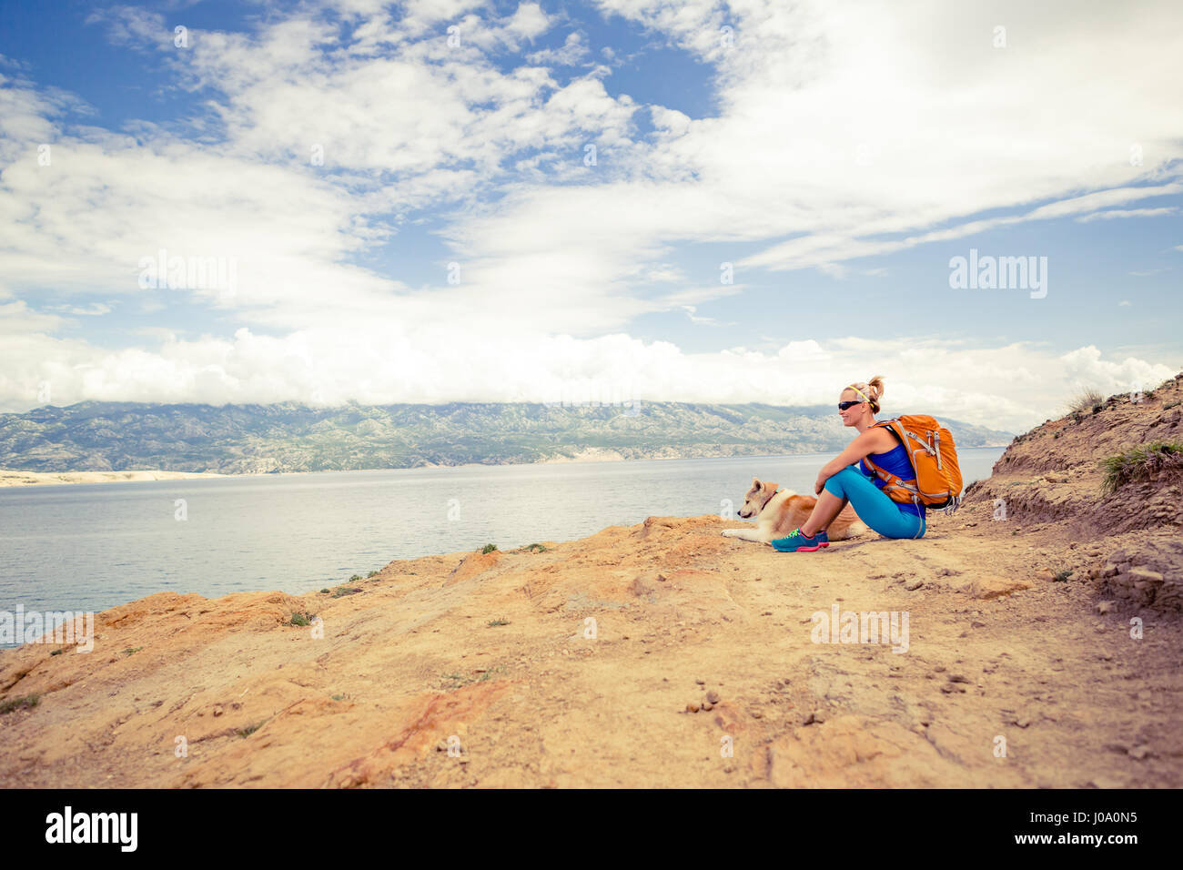 Donna escursionismo con akita inu cane sul sentiero sul mare. Ricreazione e uno stile di vita sano all'aperto in estate sulle montagne e mare natura. Bella inspirationa Foto Stock