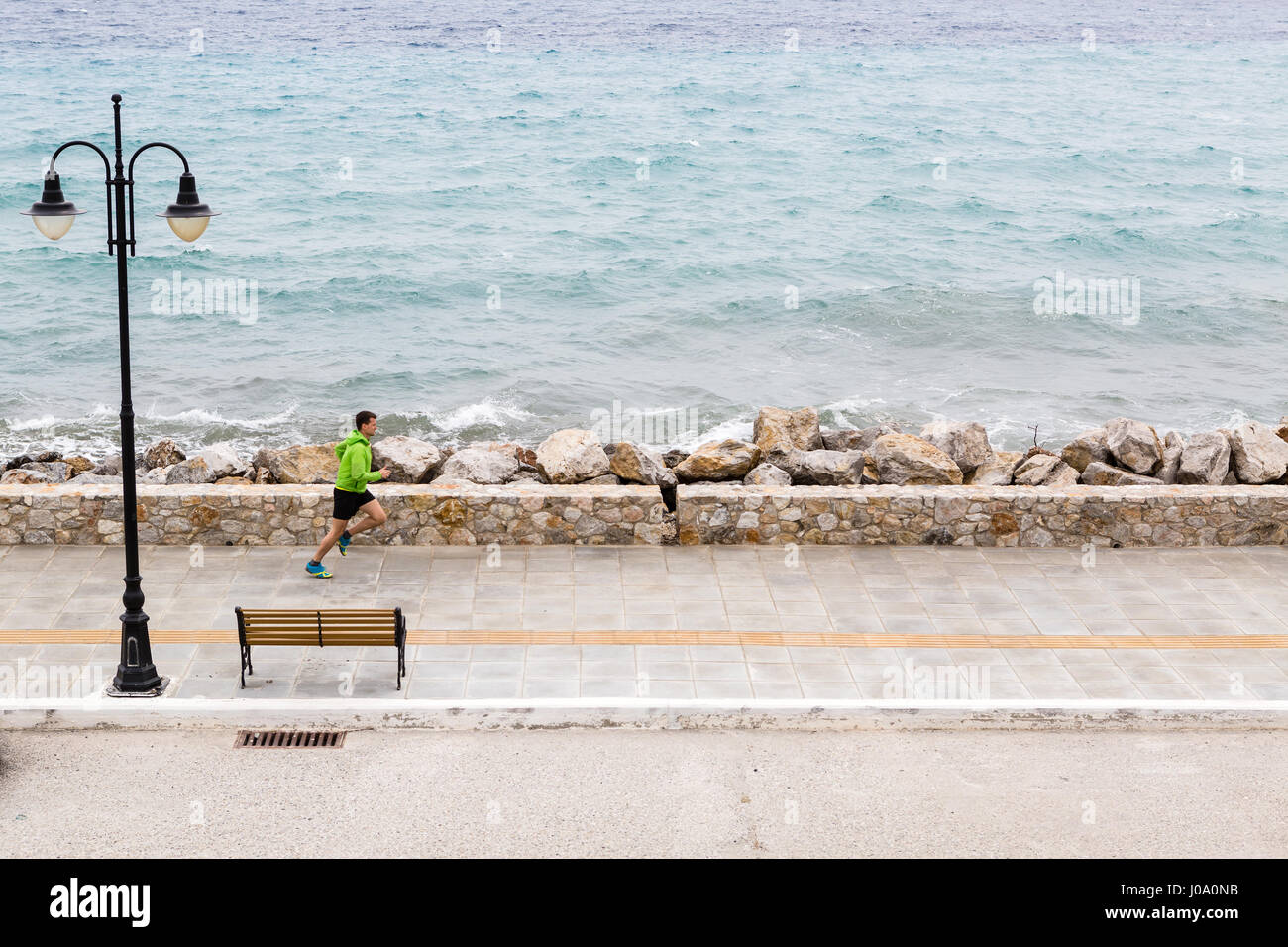 Uomo che corre su una strada di città in riva al mare a. Giovane atleta maschio e di formazione facendo allenamento all'aperto in scena urbana. Sport e fitness training ispirazione un Foto Stock