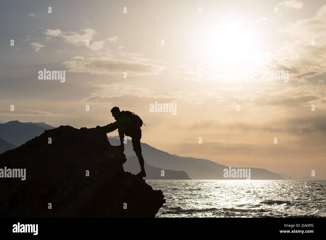 Arrampicata escursionismo silhouette di montagne e oceano, rocciatore in ispirazione panorama sul mare e sulle isole sul picco di montagna. Compiuta montare l'uomo su s Foto Stock