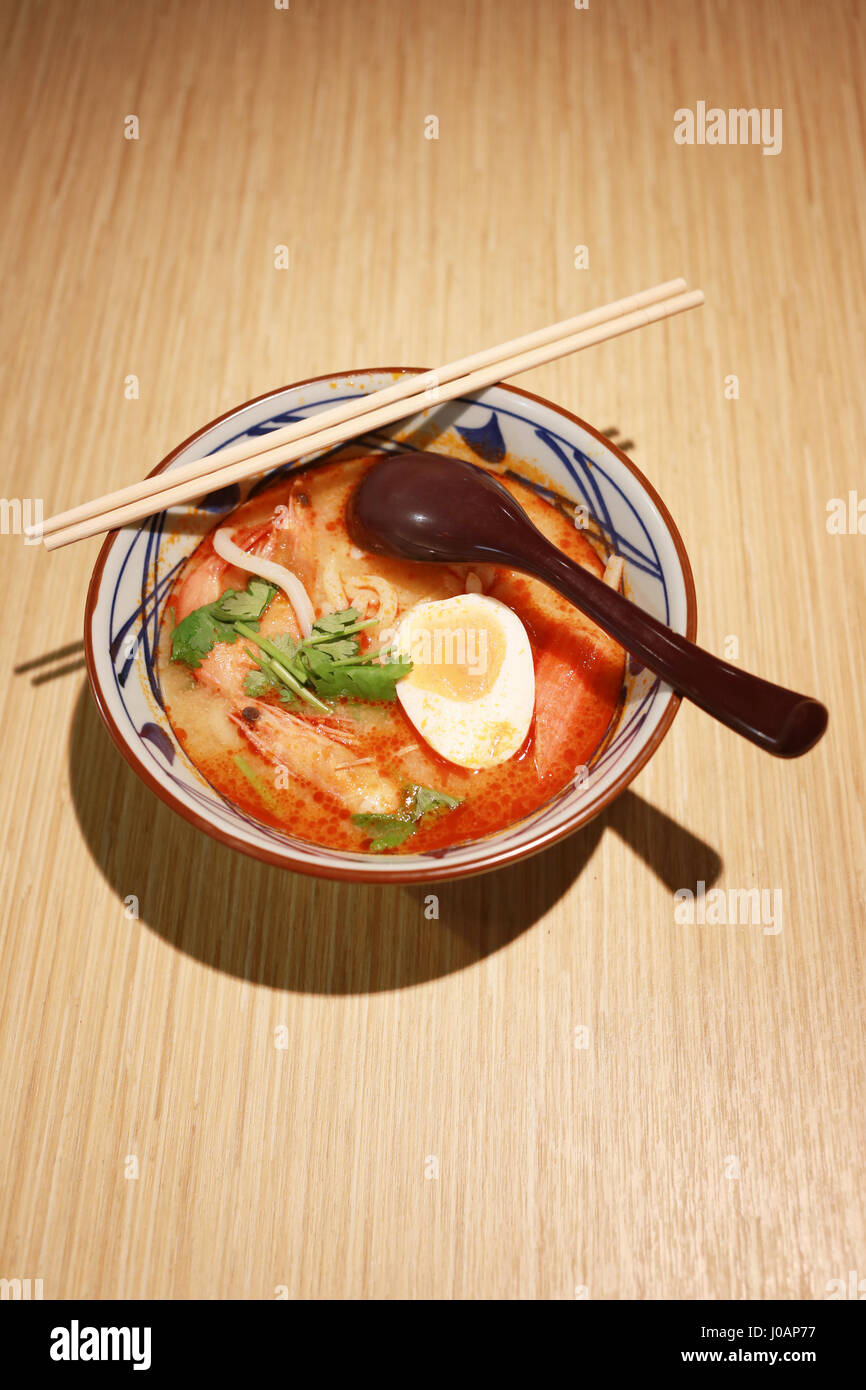 Ramen Tom Yum Goong di mix Thai alimenti e il cibo giapponese su uno sfondo di legno. Foto Stock