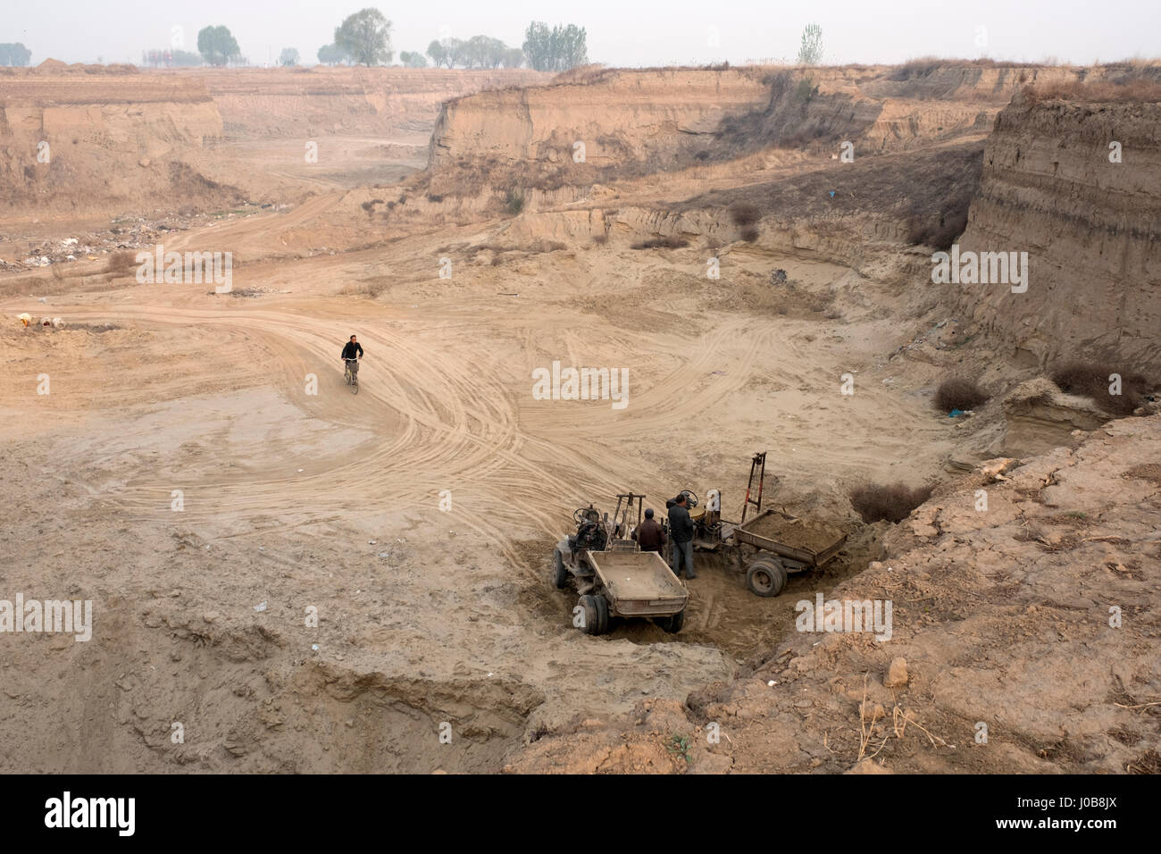 Gli uomini dragare la terra o sabbia in una grande fossa nella Xiong County, nella provincia di Hebei (Cina). 09-Apr-2017 Foto Stock