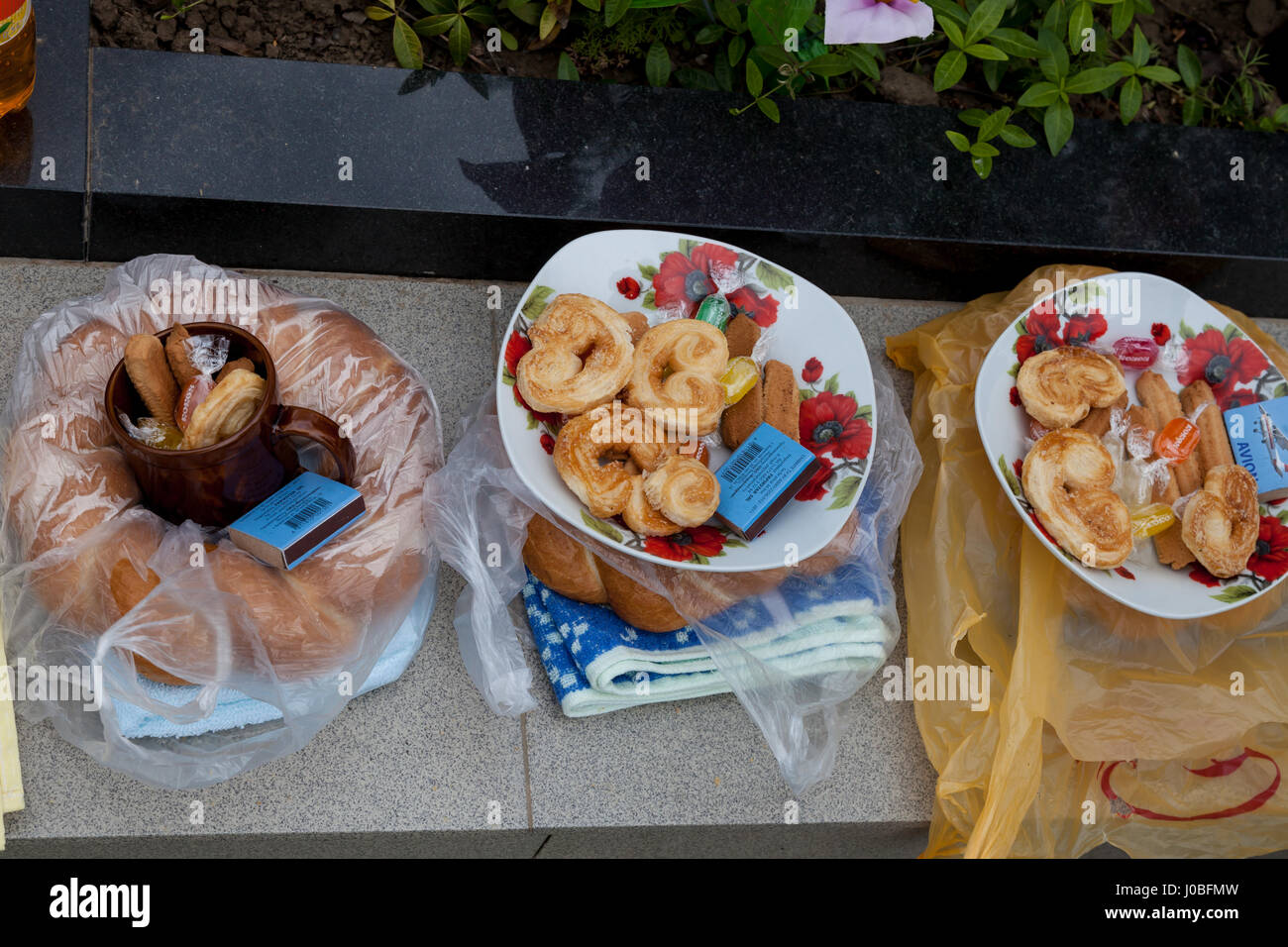 CHISINAU, REPUBBLICA MOLDOVA: Pomana, una tradizionale offerta di cibo è preparato come un regalo per gli amici e la famiglia come bene come forestieri. Visitatori in Europa il più grande cimitero sono stati innestati spezzando il pane con il morto. Ciò che potrebbe sembrare morboso è infatti una pratica tradizionale a Chisinau, in Moldavia. Le immagini mostrano le orde di persone che hanno amato-quelli sepolti in questo cimitero spooky impostazione e godendo di pic-nic intorno le tombe per commemorare il defunto in modo spettacolare. Mentre alcuni giovani da questo cristiano ortodosso di comunità può essere visto nonchalantly giocando sui loro telefoni. La tentacolare la Foto Stock