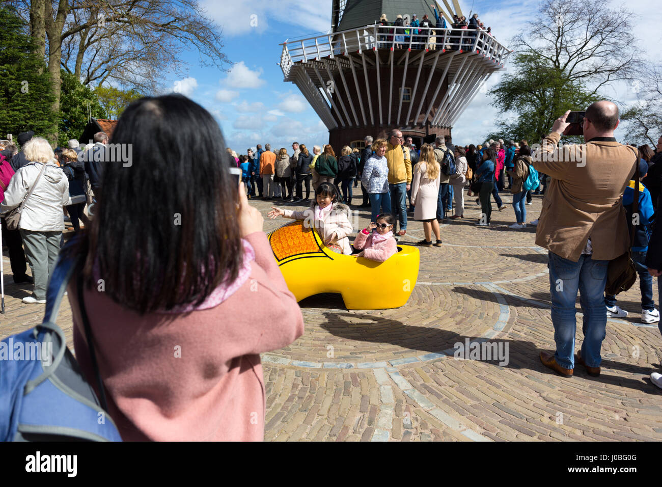 Due ragazze asiatiche in posa di un gigante di scarpa in legno con un mulino a vento in background mentre la loro madre si prende una foto con il suo telefono - Primavera 2017 in Keuke Foto Stock