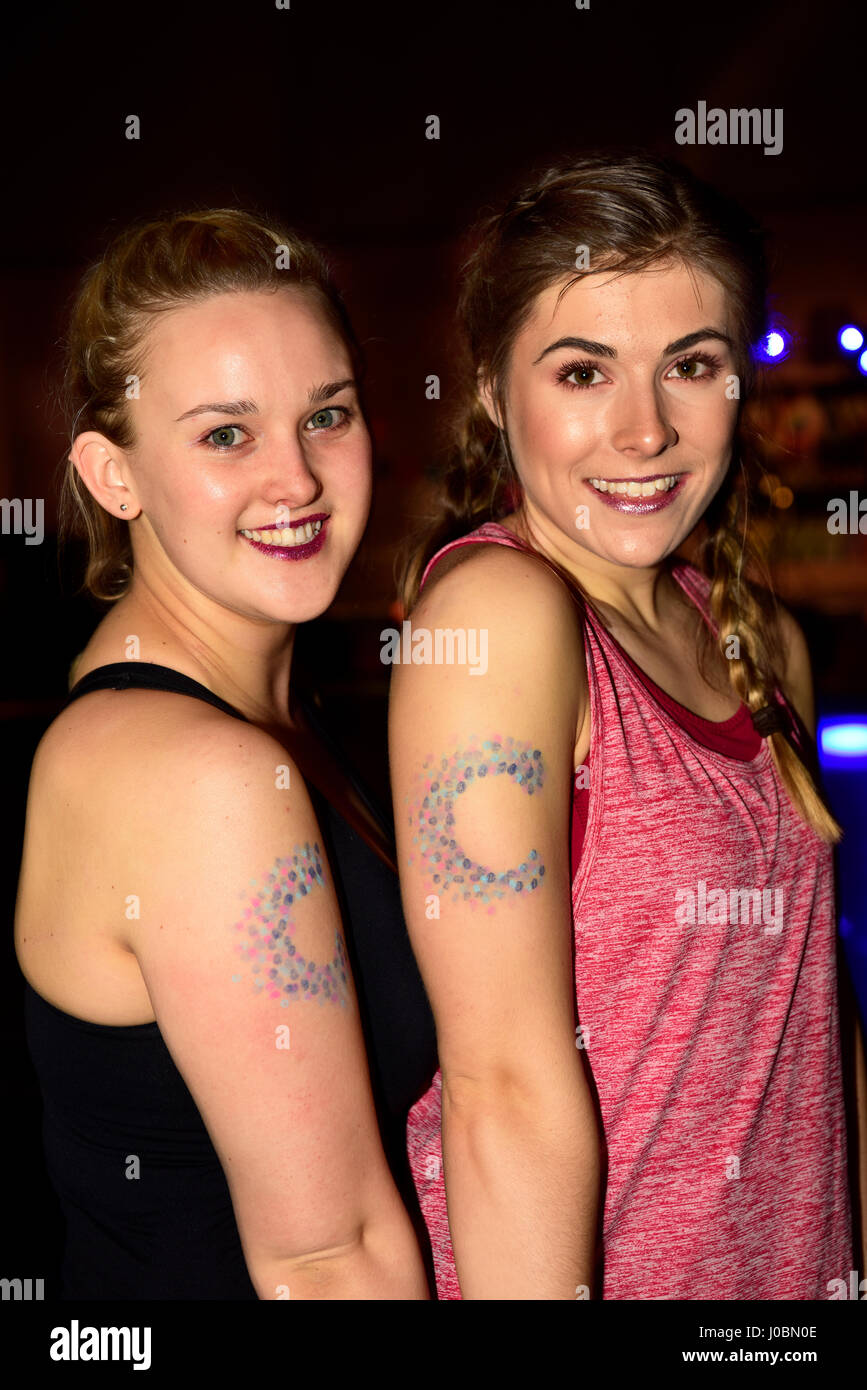 Due giovani donne, (20 e 23 anni), prendendo parte a una Carità Zumbathon per la ricerca sul cancro e indossando la ricerca sul cancro emblema sulla loro braccio, Alton, Hamps Foto Stock