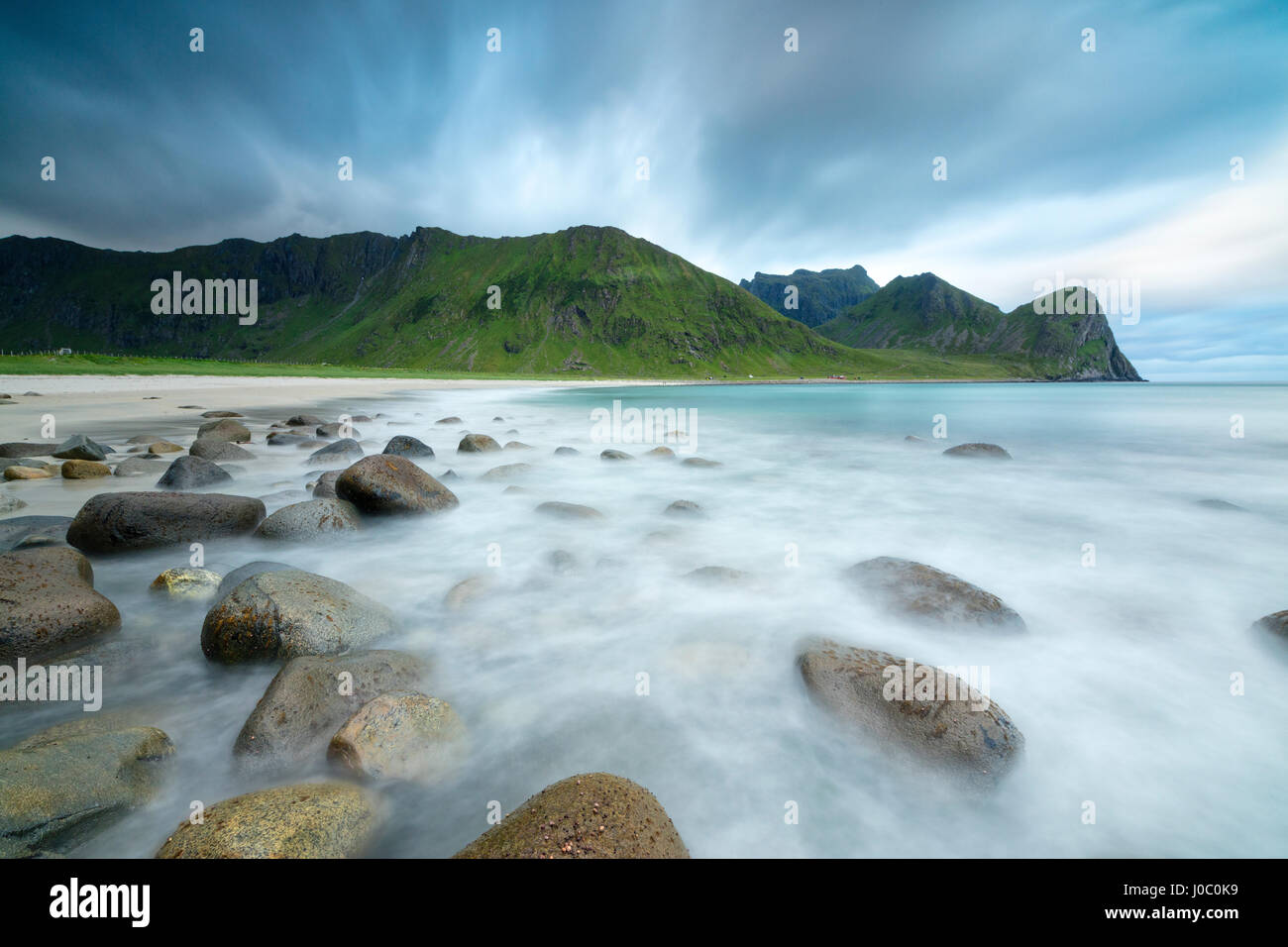 Il sole di mezzanotte si illumina le onde del mare blu, Unstad, Vestvagoy, Isole Lofoten artico, Norvegia e Scandinavia Foto Stock
