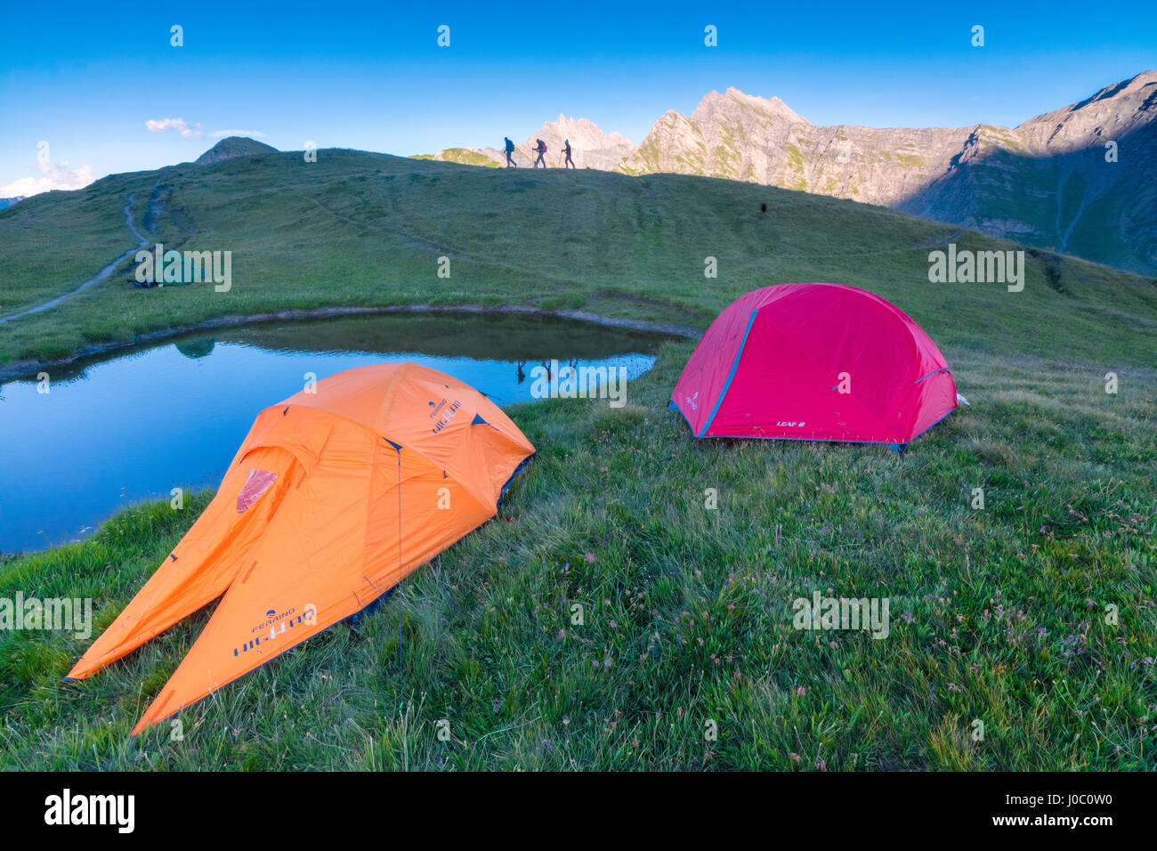 Tende da campeggio e gli escursionisti con Mont De La Saxe sullo sfondo, Courmayeur, in Valle d'Aosta, Italia Foto Stock