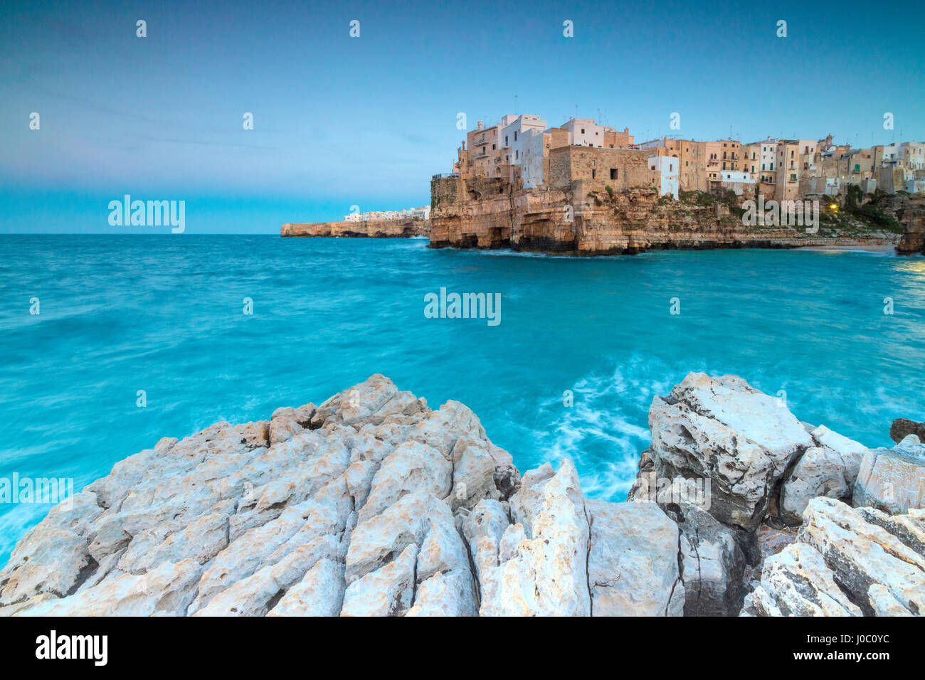 Il mare turchese al tramonto incorniciato dal centro storico arroccato sulle rocce, Polignano a Mare, provincia di bari, puglia, Italia Foto Stock