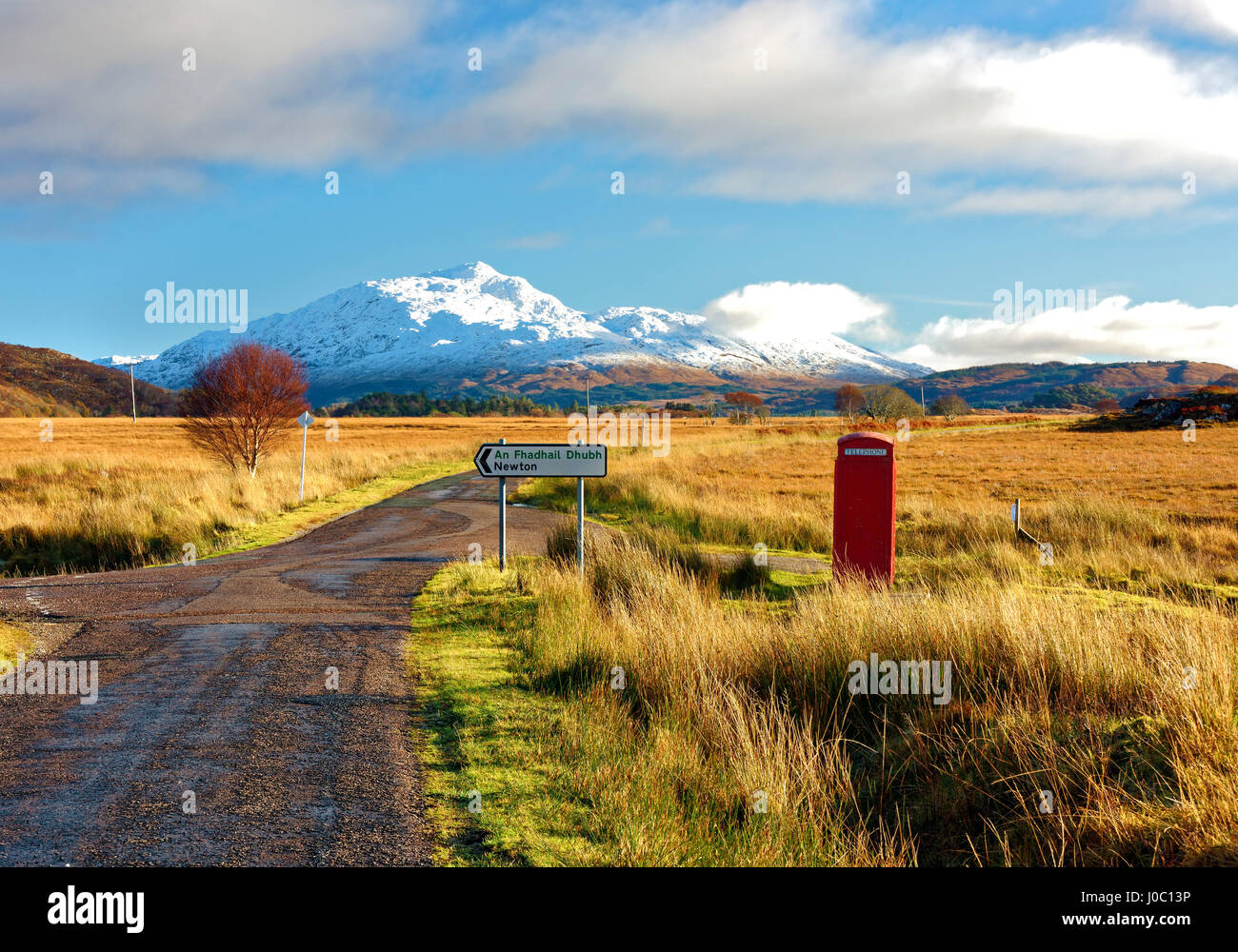 Vista invernale di un telefono rosso nella casella e la strada verso la coperta di neve Beinn Resipol mountain, Highlands scozzesi, Scotland, Regno Unito Foto Stock