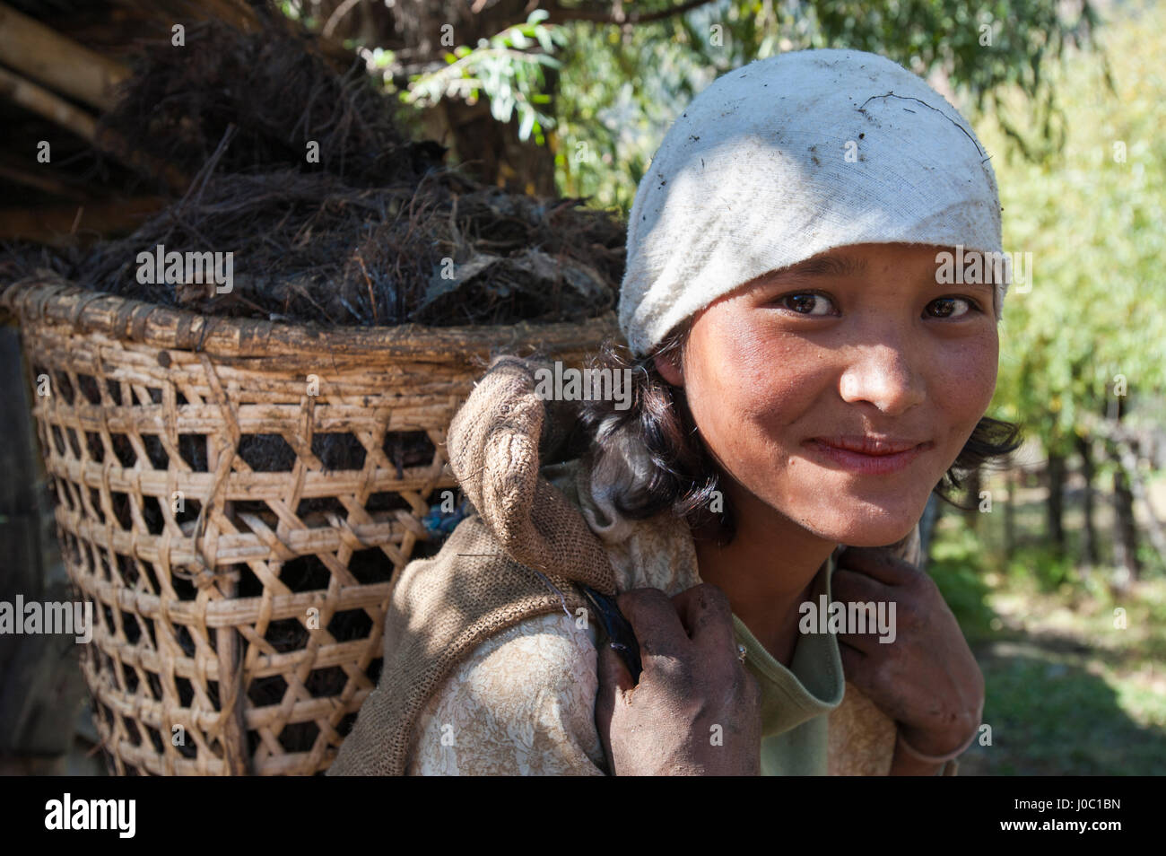 Una ragazza bhutanesi trasporta i foraggi per alimentare il suo bestiame in un villaggio vicino a paro, Bhutan, Asia Foto Stock