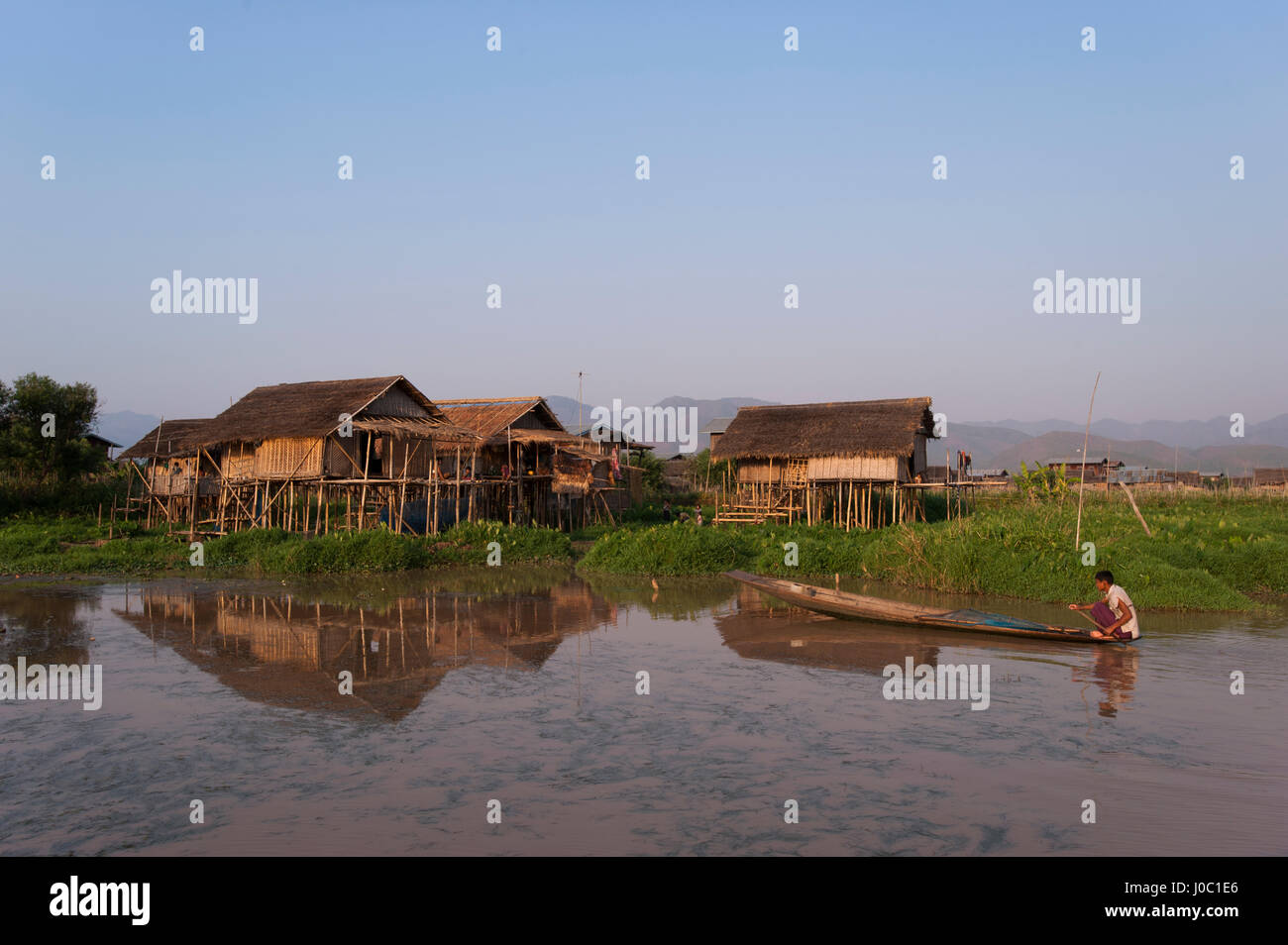 Un uomo pagaie il suo passato di canoa uno dei villaggi galleggianti sul Lago Inle, Myanmar (Birmania), Asia Foto Stock