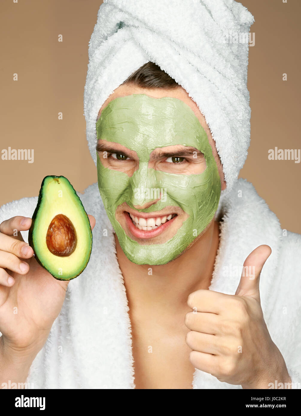 Uomo che indossa avocado maschera viso e mostra Thumbs up. Ritratto di uomo  felice con maschera al viso e azienda fetta di avocado. Beauty & Skin care  concept Foto stock - Alamy