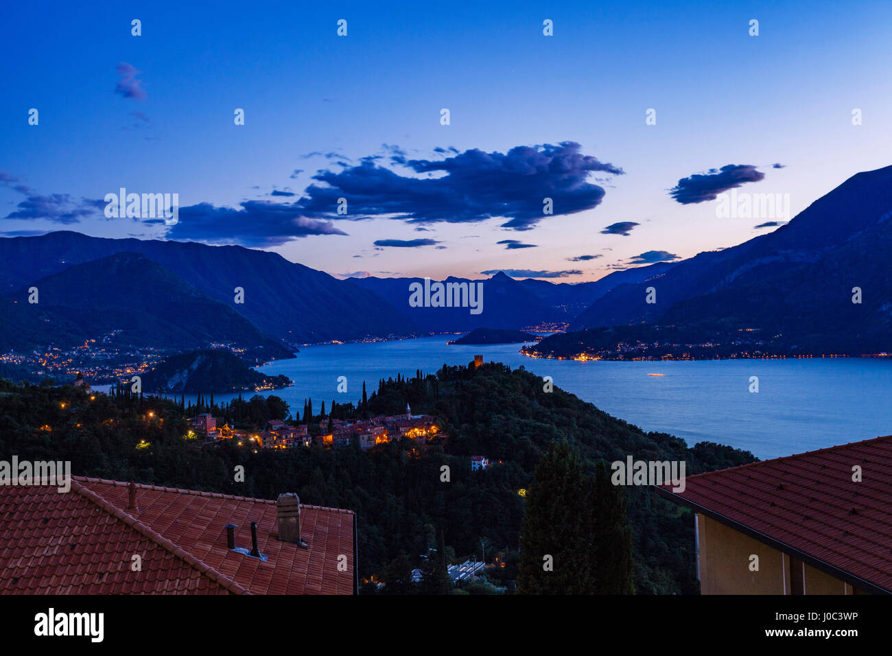 Edifici illuminata di sera dal lago di Como, Varenna, Italia Foto Stock