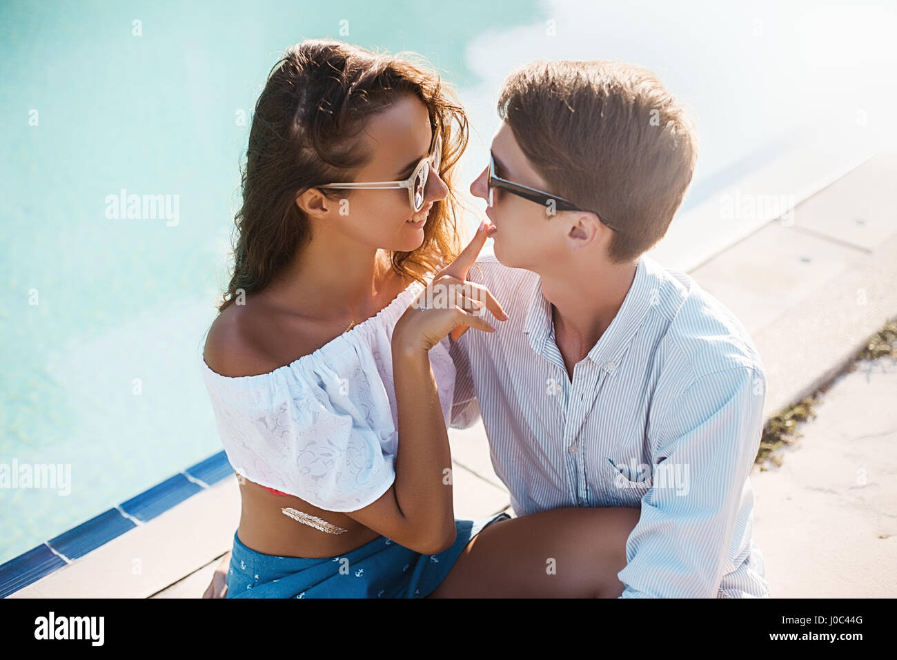 Giovane donna con il dito sul ragazzo della labbra a bordo piscina, Koh Samui, Thailandia Foto Stock