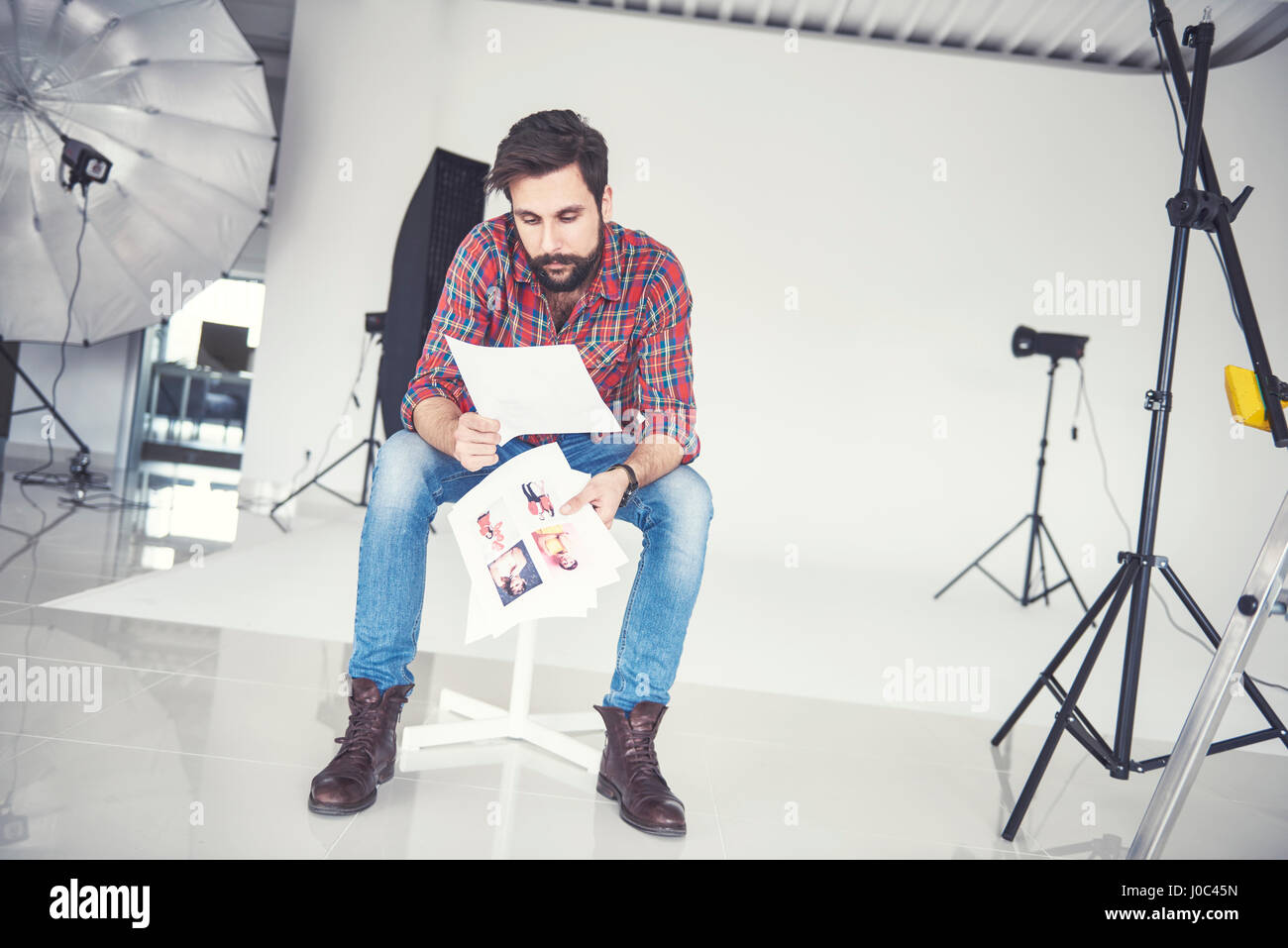Fotografo maschio guardando le fotografie in studio Foto Stock